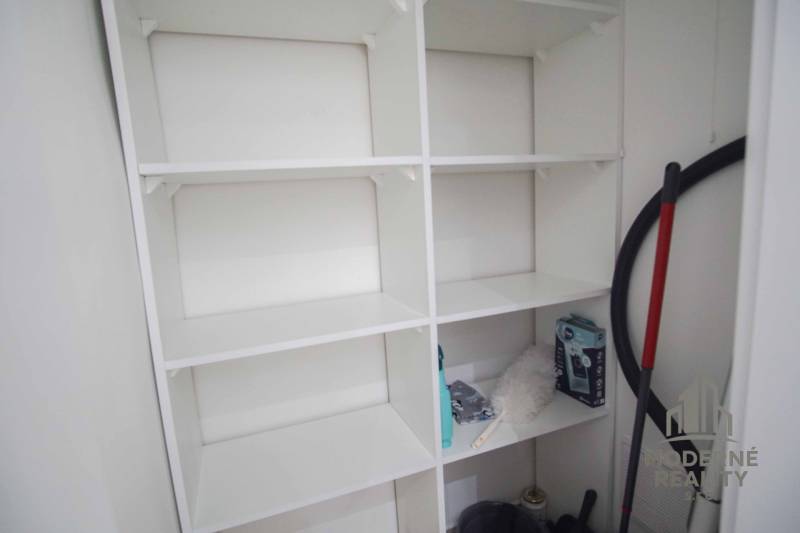 Storage space with white shelves in a 2-room apartment.