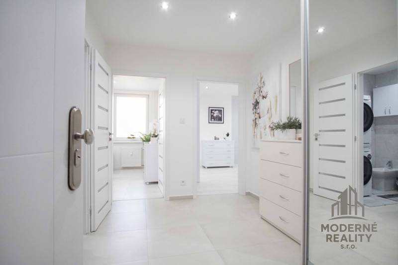 A bright entrance hallway in a 2-room apartment with modern decor and hanging paintings.