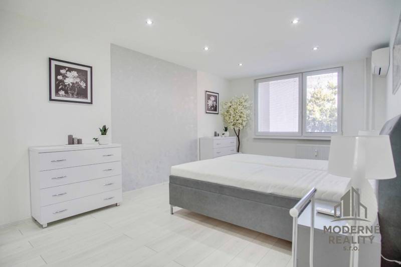 A bright bedroom in a two-room apartment with white furniture and decorations.