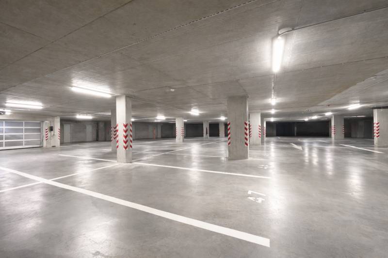Spacious garages with marked parking spaces, bright lighting, concrete pillars.