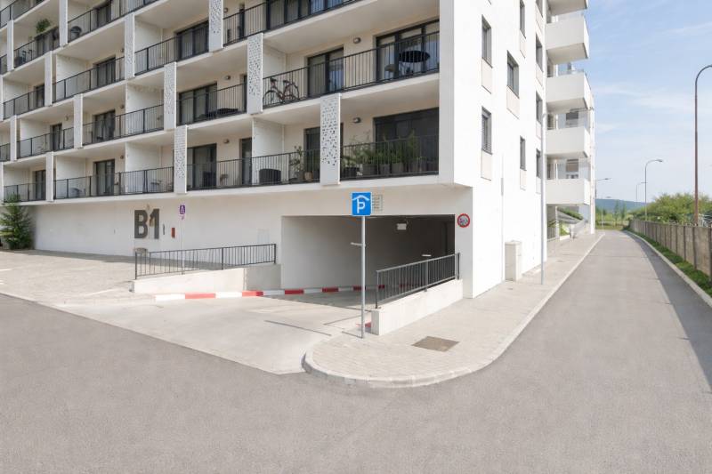 Residential building with parking entrance in Bratislava-Rača on Eduarda Wenzla Street.