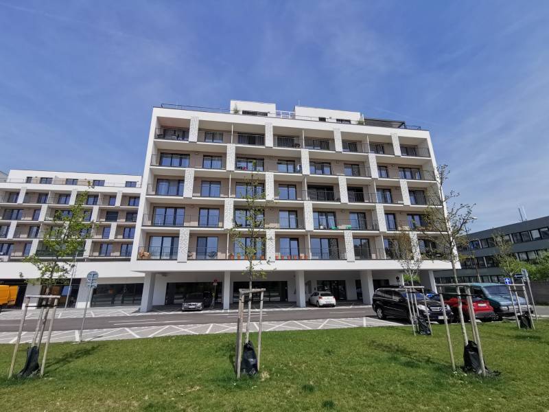 Apartment building on Eduarda Wenzla Street with parking and garages in the foreground.