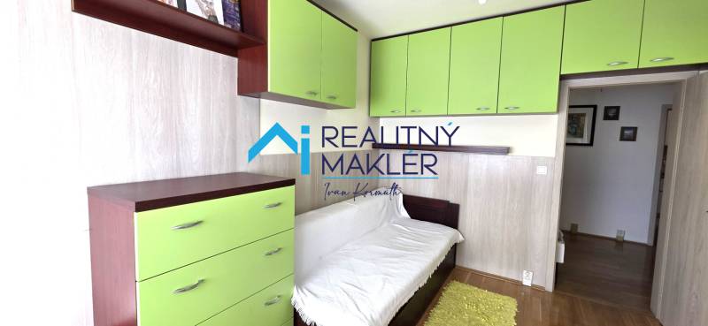 A room in a 3-room apartment with a white sofa, green cabinets, and a wooden decor floor.