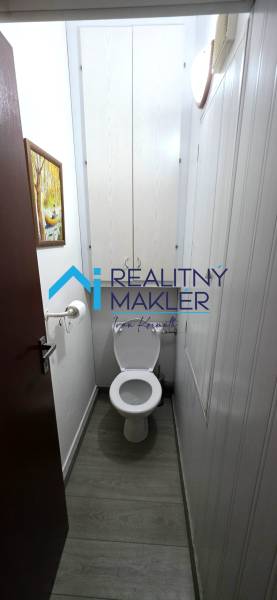 A toilet with a wooden decor floor in a 3-room apartment.