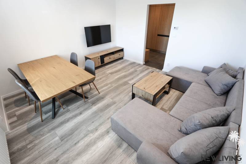 Living room in a 3-room apartment with a wooden decor floor, sofa, and TV.