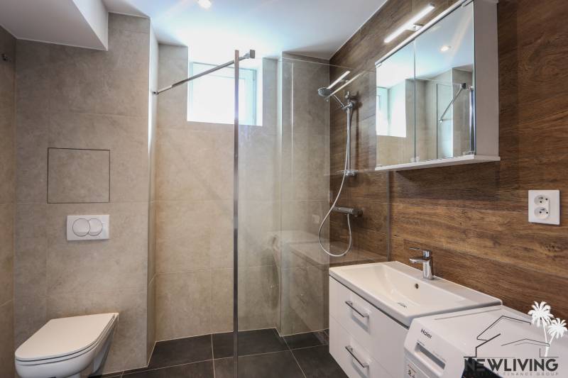 A bathroom in a 3-room apartment with modern sanitary fixtures and a wooden decor floor.