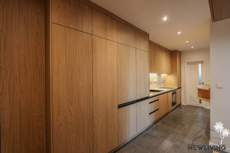 A kitchen in a 3-room apartment with a wood-patterned floor and built-in appliances.