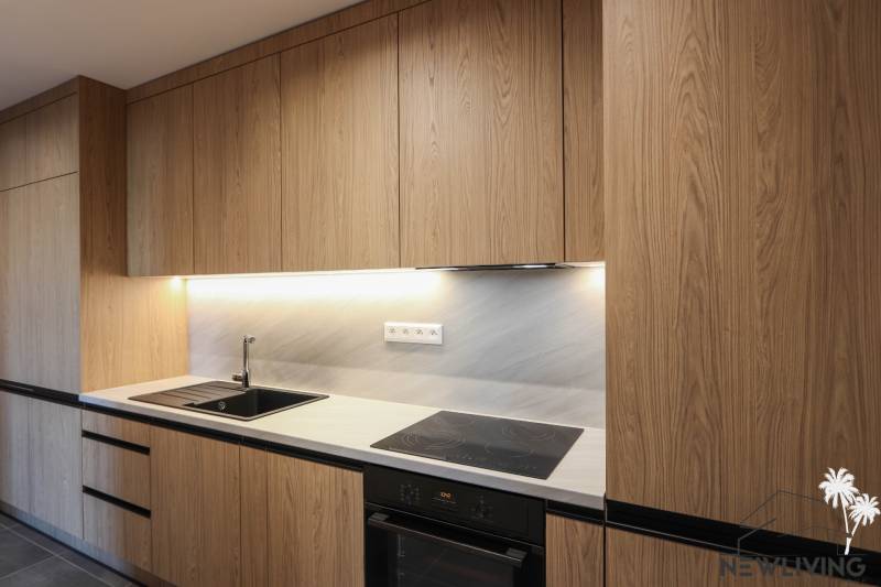 A kitchen in a 3-room apartment with a wooden decor kitchen unit and built-in appliances.