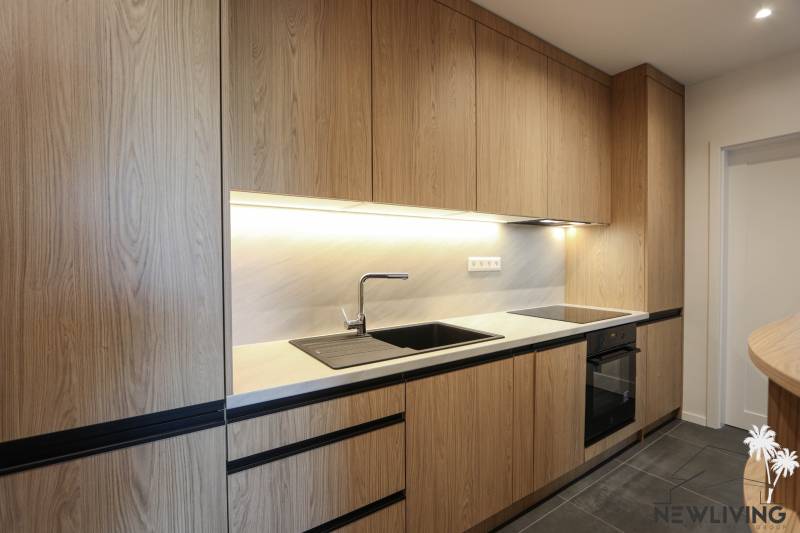 A kitchen with wooden decor, black details, built-in appliances in a 3-room apartment.