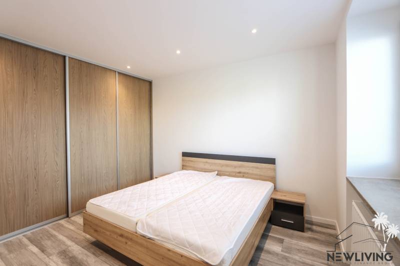 A bedroom in a 3-room apartment with a wood-patterned floor and a large built-in wardrobe.