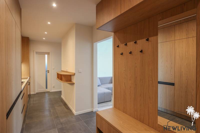 A hallway with a wooden decor floor and wardrobe closets in a 3-room apartment.