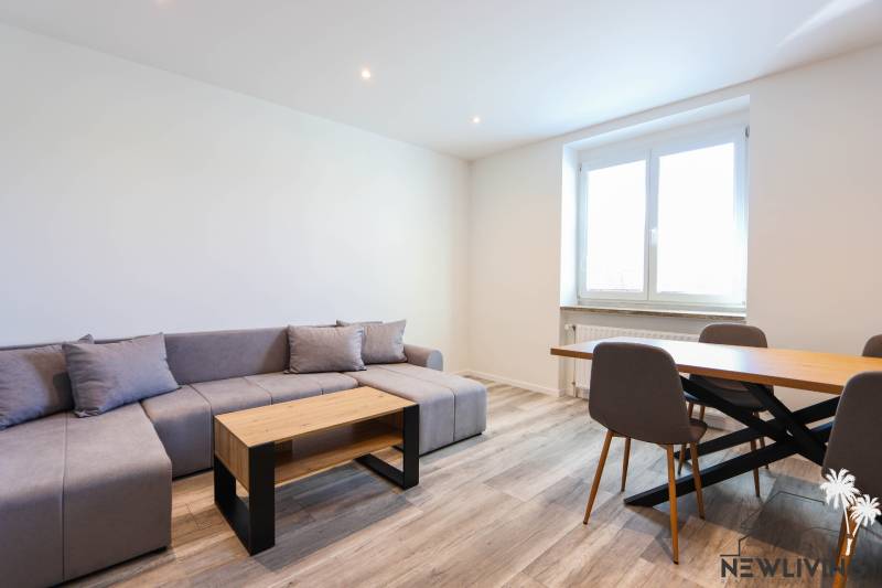 Living room with a corner sofa, dining table, and wooden decor flooring.