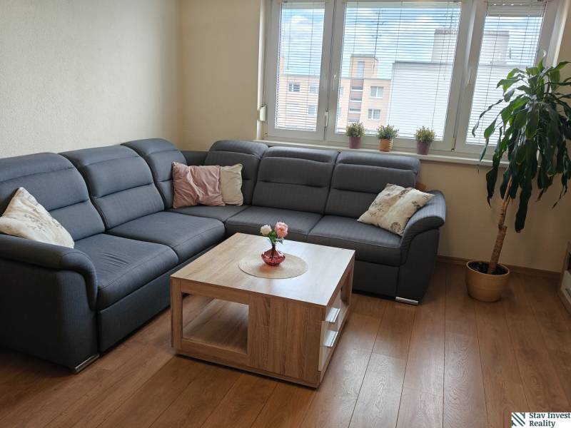 Living room in a 3-room apartment with a corner sofa and a wooden decor floor.