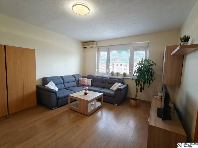 Living room with a corner sofa, wooden decor flooring, and a TV in a 3-room apartment.