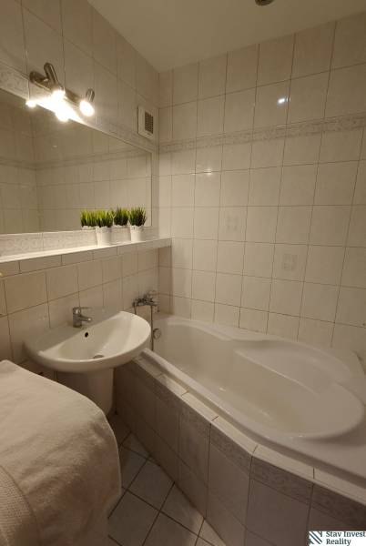 Bathroom with a bathtub and a sink in a 3-room apartment, white tiles and decorations.