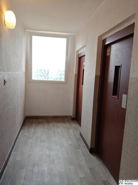 A hallway with elevators and a wooden decor floor in a 3-room apartment.