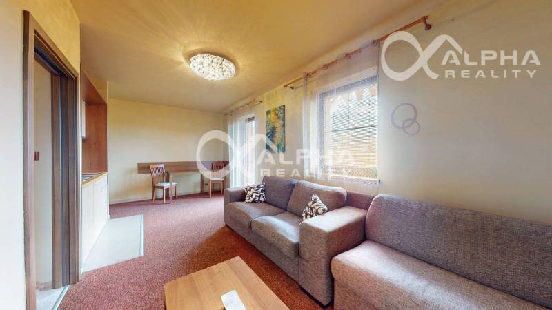 Living room in a two-room apartment with a sofa, dining table, and curtains.