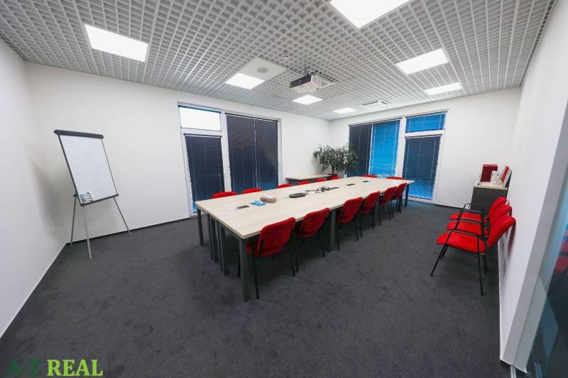 Conference room with a long table, red chairs, and a flipchart in the offices.