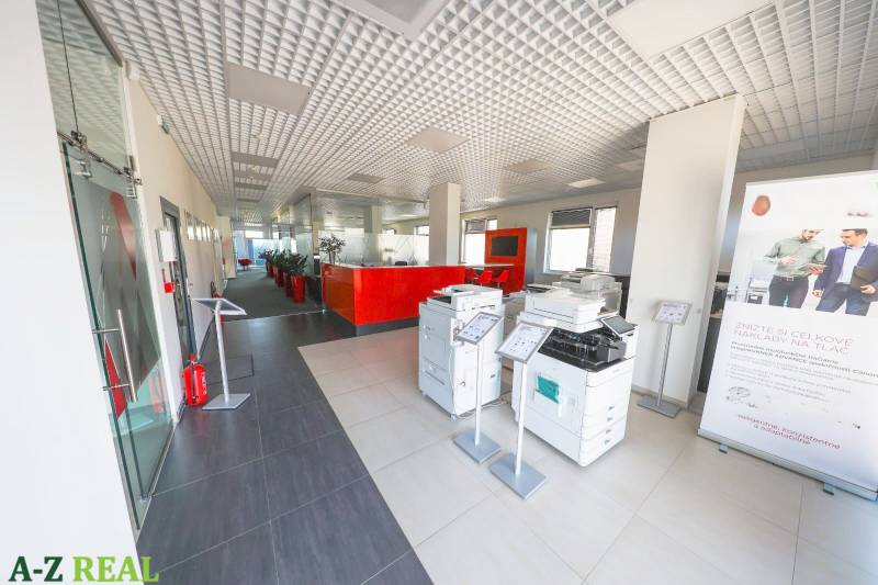 The interior of an office with printers, a red reception desk, and a high ceiling.