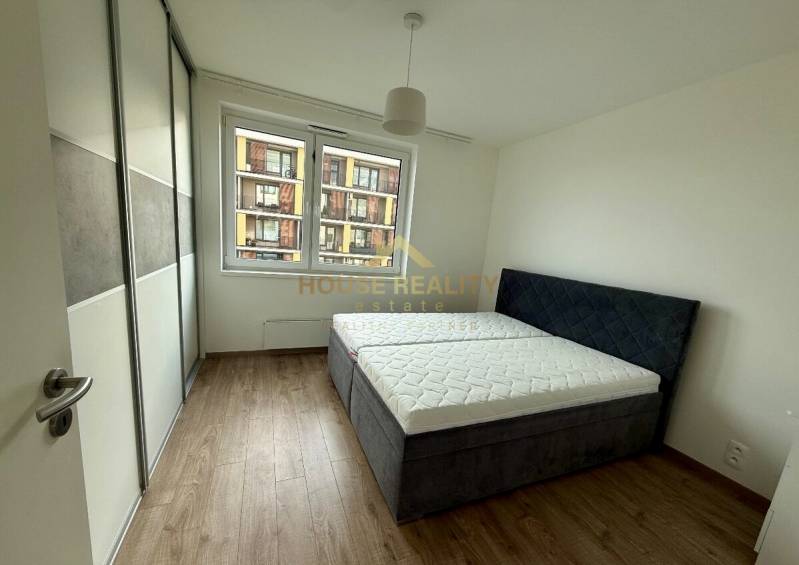 Bedroom with a built-in wardrobe, double bed, and wooden decor flooring in a two-room apartment.