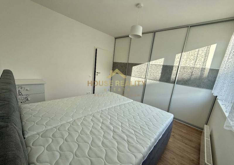 Bedroom with a bed and built-in wardrobe in a 2-room apartment, floor with wooden decor.