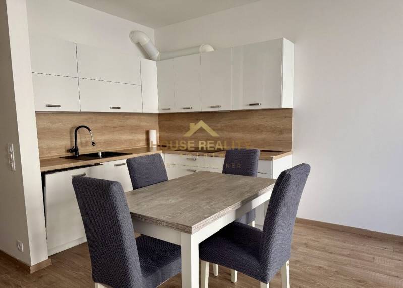 A kitchen in a 2-room apartment with white cabinets and a wooden decor floor.