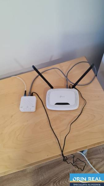 A table with a network device and a router in a studio apartment, floor with wooden decor.