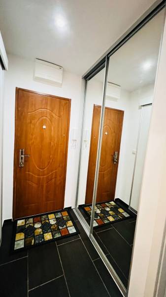 A hallway in a 3-room apartment with doors, a mirrored wardrobe, and a colorful carpet.