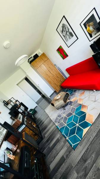 Living room in a 3-room apartment with a red sofa and a wooden decor floor.