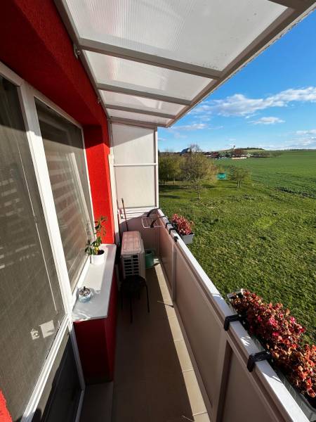 The balcony of a 3-room apartment in Gbeľy with a view of green meadows and flowers.