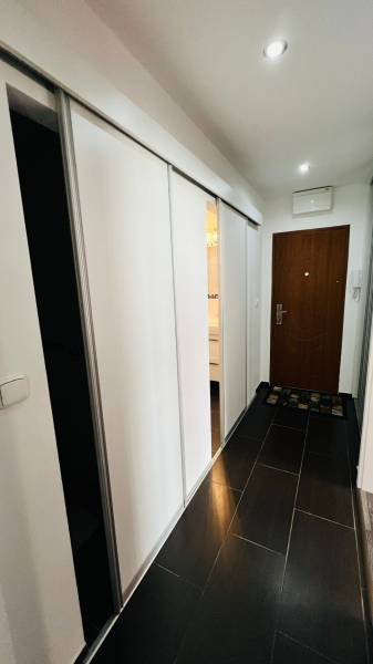 A hallway in a 3-room apartment with sliding doors and a dark brown floor.