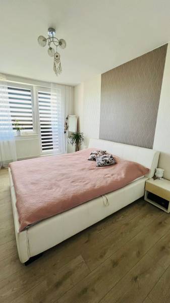 A bright bedroom with a large bed, a mirror, and a wooden decor floor in a 3-room apartment.