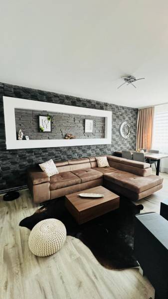 Living room in a three-room apartment with a wooden decor floor and a corner sofa.