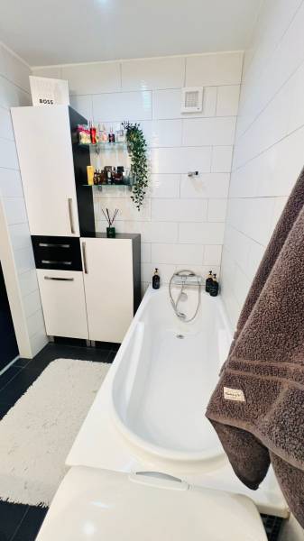 Bathroom with a bathtub, cabinets, and decorations in a 3-room apartment.