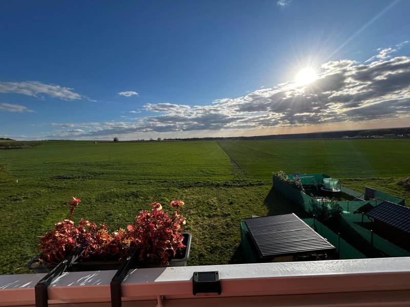 A view of the vast green landscape and a balcony with flowers in Gbelá.