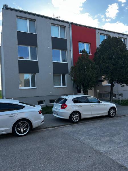 An apartment building in Gbely with a modern facade and parked cars in front of a 3-room apartment.