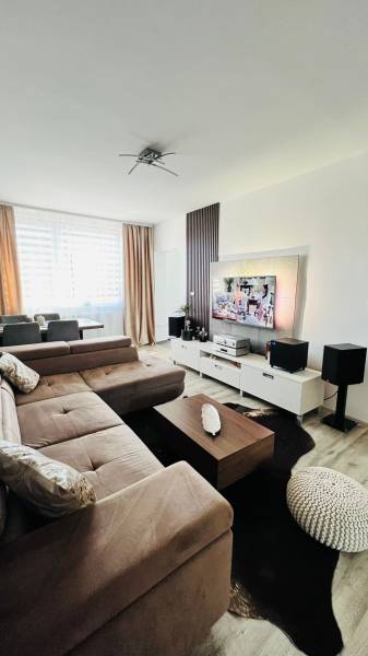 Living room with a corner sofa, TV stand, and wooden decor flooring.