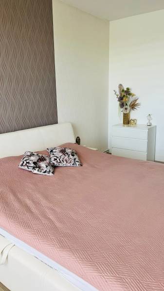 A bedroom in a 3-room apartment with a bed, decorative pillows, and ornamental wallpaper.