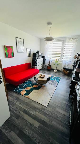 A room with a red sofa and a wooden decor floor in a 3-room apartment.
