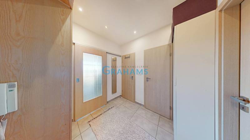 The entrance hall of a 2-room apartment with tiles, light doors, and a mirror.