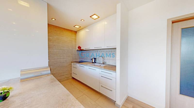 A kitchen in a 2-room apartment with white cabinets and a wooden decor floor.