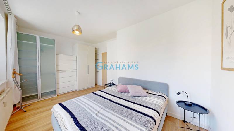 Bedroom in a 2-room apartment with a bed, wardrobes, and a floor with a wooden decor.