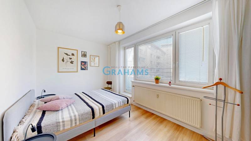 A bright bedroom in a two-room apartment with decorations on the white wall.