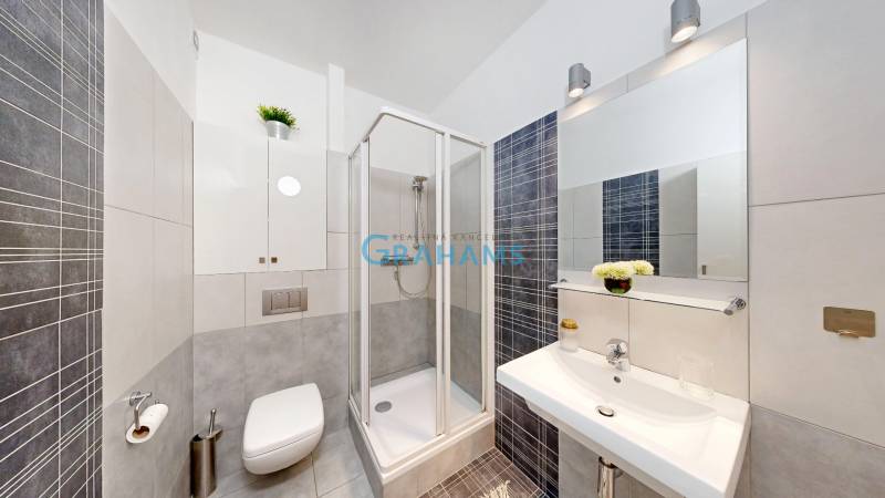 Bathroom in a 2-room apartment with a shower and tiles in modern grey color.