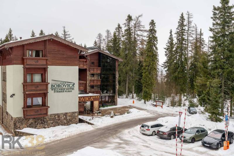 A recreational apartment in Poprad surrounded by a snowy forest and parking space.