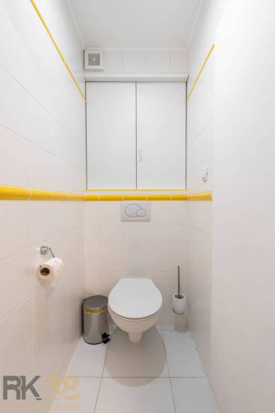 Bathroom with white tiles and yellow details in the Holiday Apartment.