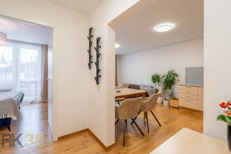 Interior of a holiday apartment with a wooden decor floor, dining area, and bedroom.
