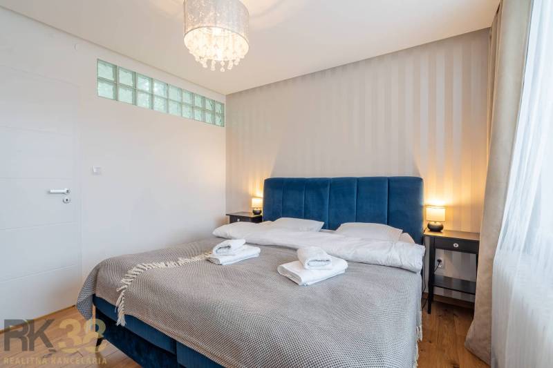 Bedroom in a holiday apartment with a double bed and wooden decor flooring.