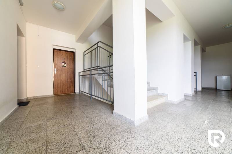 A hallway with a stoneware floor and a staircase in a 2-room apartment.