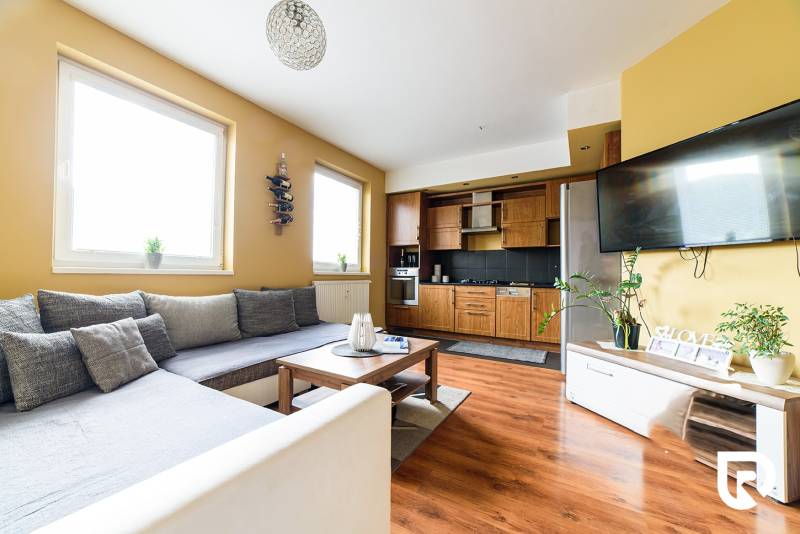 Living room in a 2-room apartment with a kitchenette and a floor with a wooden decor.